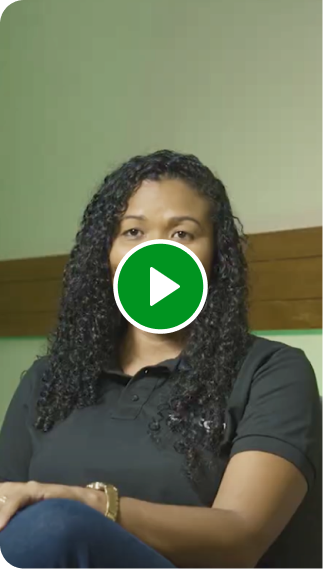 Consultora Renda Extra Ton. Mulher sorrindo, sentada em uma cadeira, rodeada por uma parede verde.